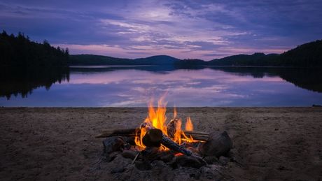 Burning campfire on the beach at dusk while on kayak camping trip.