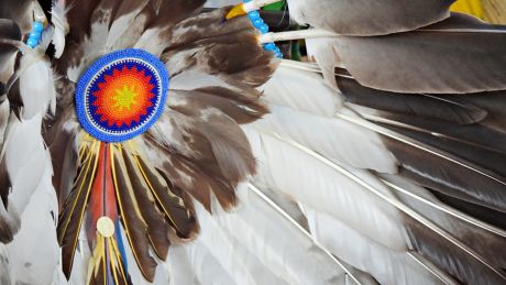 Close-up of Native American regalia featuring eagle feathers and colourful beadwork.